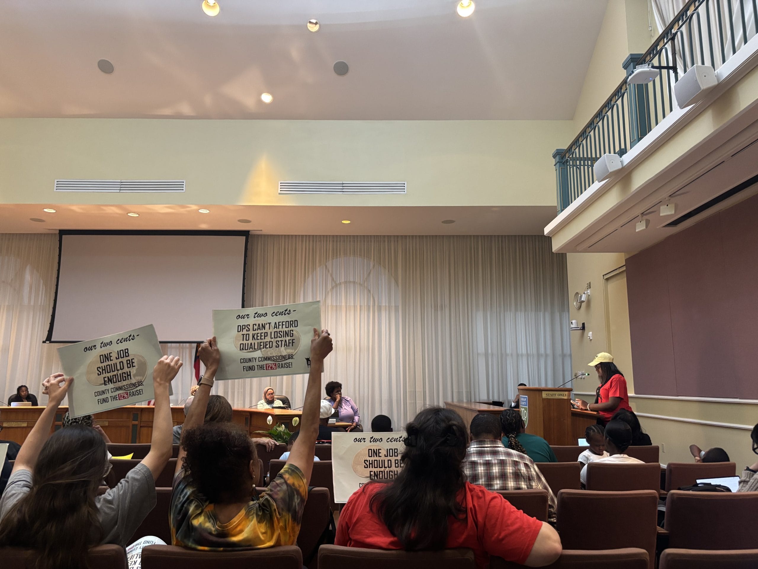 Create a 10-word scroll-stopping headline for: DAE Keeps Pressure on County to Raise Durham Public Schools Wages | Vibe NC